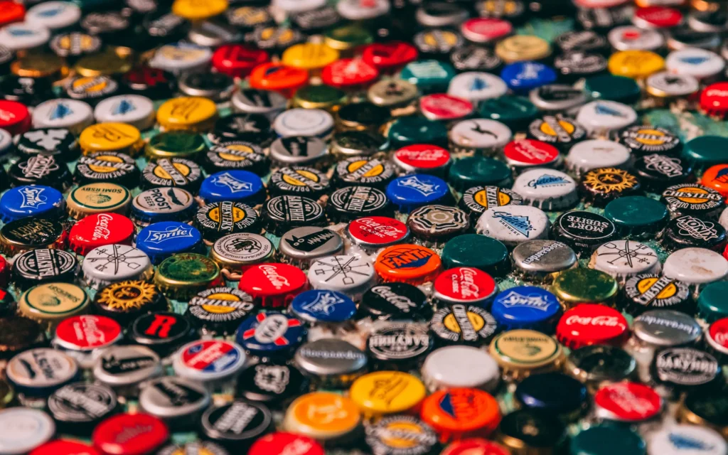 Close-up of assorted branded bottle tops including Coca-Cola, Fanta, Sprite and craft drinks.