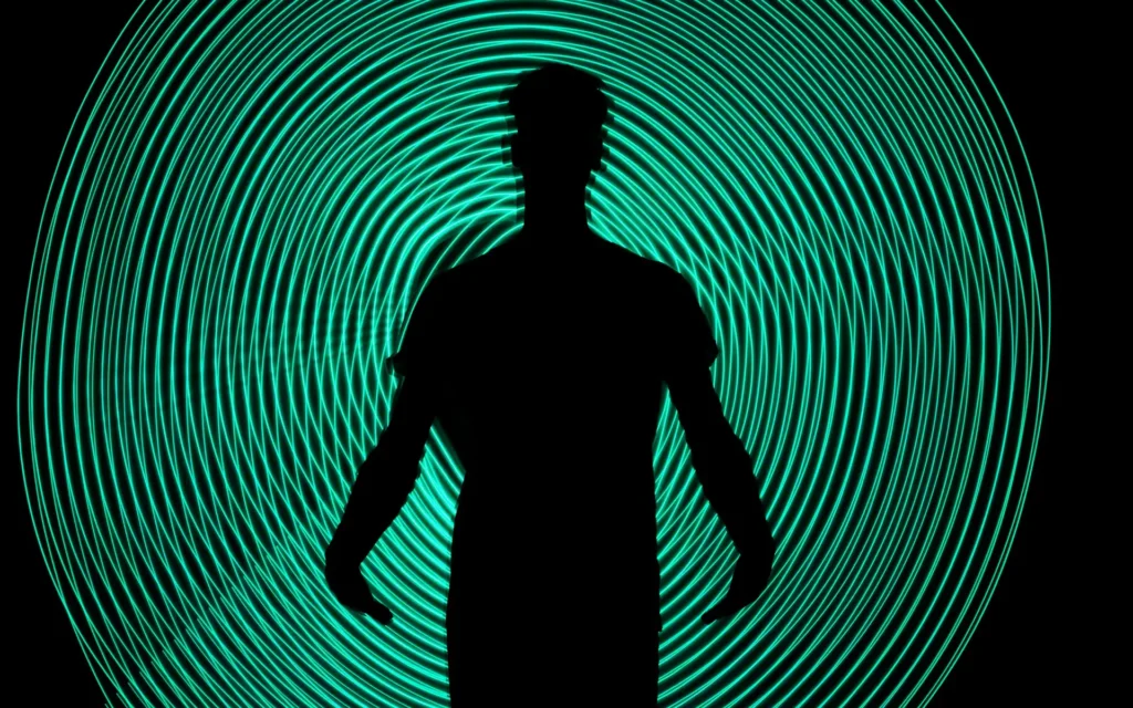 Silhouette of a person standing in front of concentric glowing teal light rings, symbolising restricted advertising