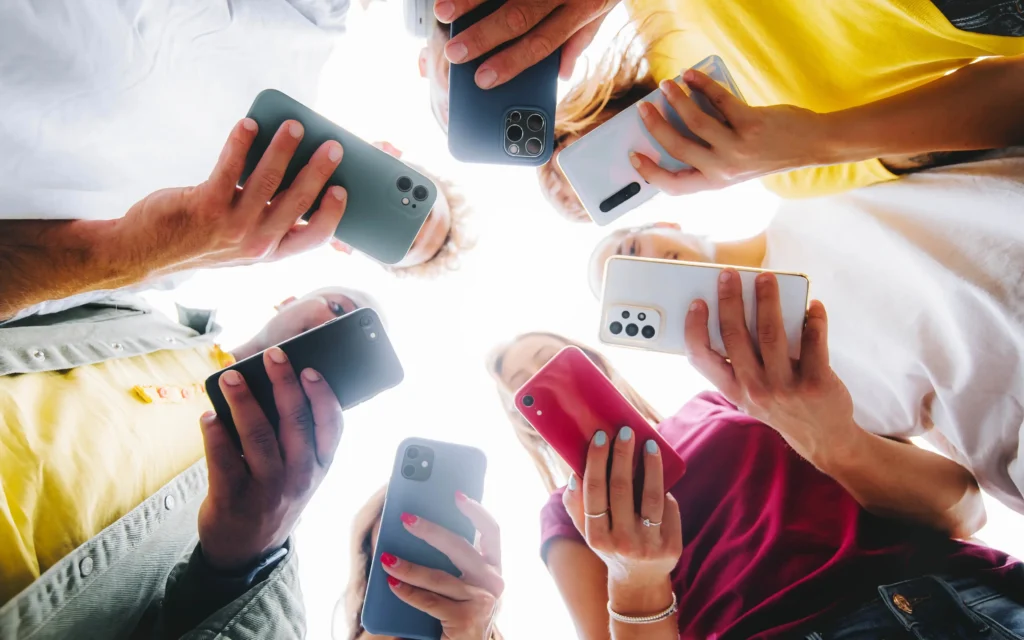 Group of people standing in a circle holding smartphones, symbolising social media connectivity.