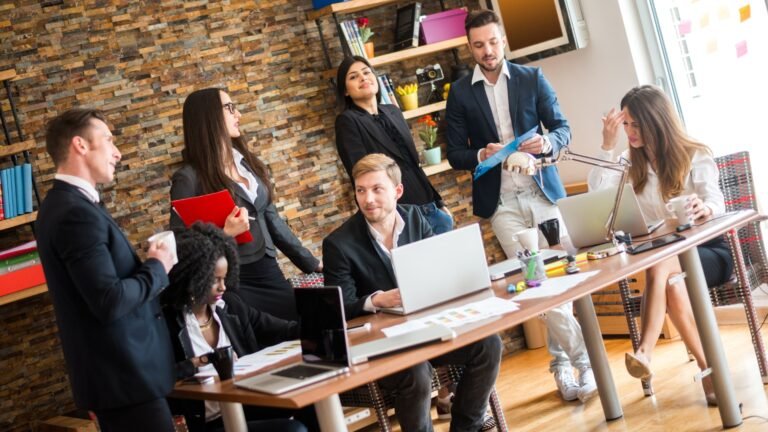 Team of professionals collaborating in a modern office with laptops, documents and coffee